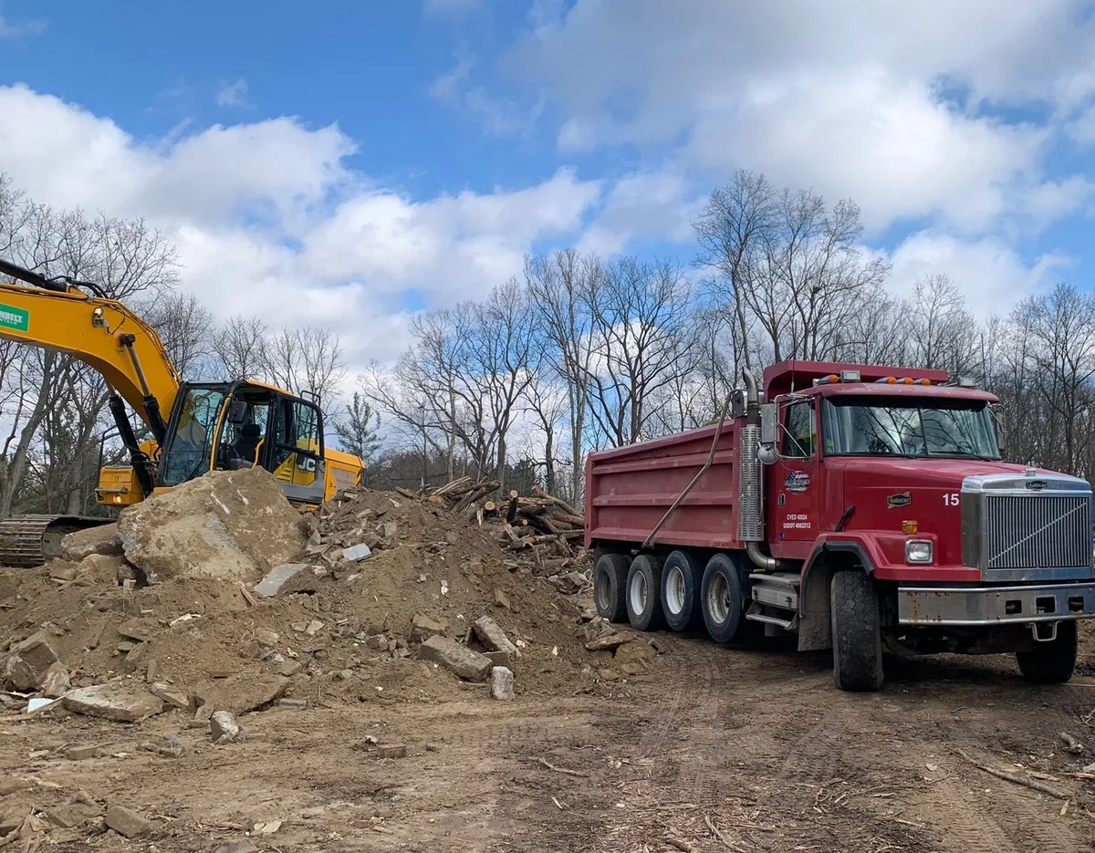Excavator and dump truck on an active lot clearing site